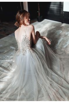 a woman in a wedding dress sitting on the floor with her back to the camera