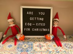 two elfs sitting on top of a bed next to a sign that says are you getting egg - cited for christmas