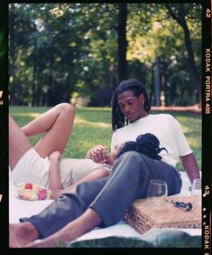 two people sitting on a blanket in the grass