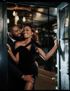 a man and woman hugging each other in front of a window