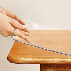 a person is holding the edge of a table with a piece of clear plastic on it