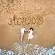 an aerial view of two people holding hands and writing on the sand at the beach