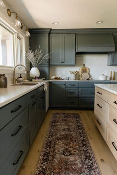 a large rug is in the middle of a kitchen with gray cabinets and white counter tops