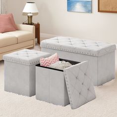 two grey storage benches in the middle of a living room with white carpet and pink pillows