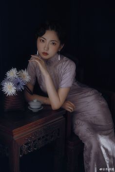 a woman sitting at a table with flowers in her hand