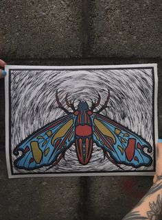 a person holding up a drawing of a bug