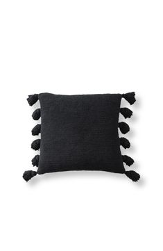 a black pillow with tassels on the front and back, against a white background