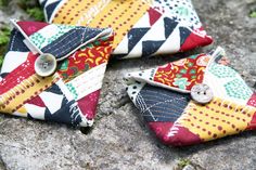 four pieces of fabric with buttons on them sitting on the ground next to some rocks