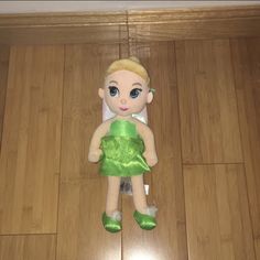 a stuffed toy doll is sitting on the floor with its green dress and matching shoes