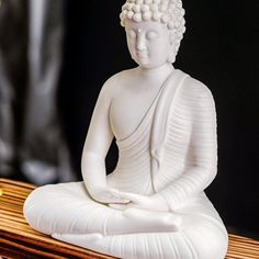 a white buddha statue sitting on top of a wooden table