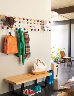 there is a coat rack on the wall next to a bench with shoes and purses