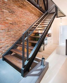 an open staircase leading up to a kitchen with brick walls and steel handrails