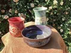 two vases sitting on top of a towel next to each other in front of flowers