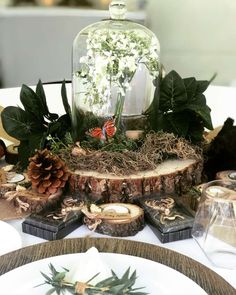 a table topped with a glass dome filled with flowers and greenery on top of wooden slices