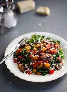 a white plate topped with a salad covered in lots of veggies and cheese