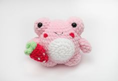 a pink crocheted stuffed animal holding a strawberry