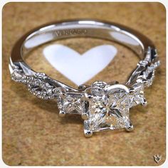 a heart shaped diamond ring sitting on top of a table