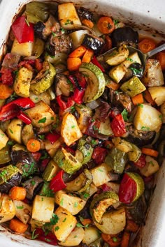 a casserole dish filled with vegetables including carrots, zucchini and peppers