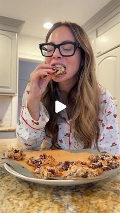 a woman in glasses is eating pizza at the kitchen table