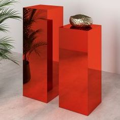 two tall red vases sitting next to each other near a potted plant on a table