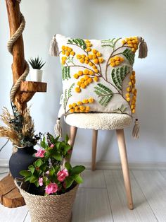 a white chair with yellow flowers on it next to a potted plant and a wooden post