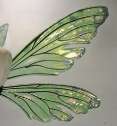 a white flower with green wings hanging from it's side