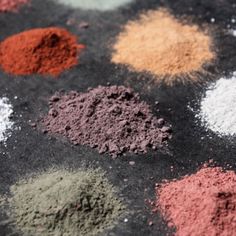 various colored powders are arranged on a black tablecloth with white and red dots