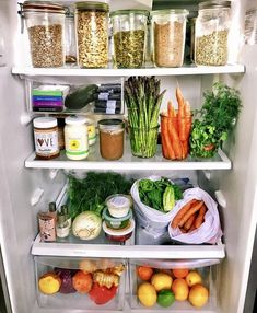 an open refrigerator filled with lots of different types of vegetables and food in containers on shelves