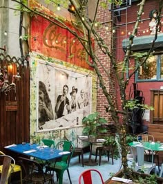 an outdoor restaurant with tables and chairs in front of a large painting on the wall