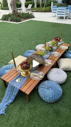 a picnic table set up on the grass with plates and bowls of food sitting on it