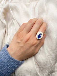 a woman's hand with a blue and white ring on it