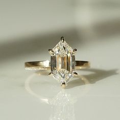 an engagement ring with a large diamond in the center on a white surface, close up