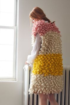 a woman is standing in front of a radiator wearing a multicolored skirt