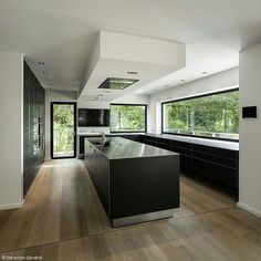 a modern kitchen with black cabinets and counter tops, along with an island in the middle