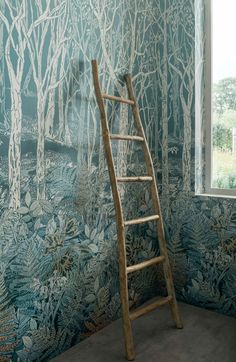 a ladder leaning against a wall in front of a window with trees painted on it