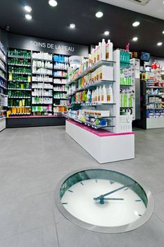 a large clock inside of a store filled with lots of bottles and other items on shelves