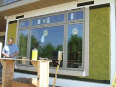 a man standing in front of a building with windows that have been painted green and yellow