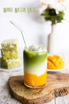 a drink with a straw in it sitting on a cutting board next to some food