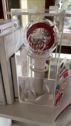 a white and red object in a clear case on top of a table next to some books