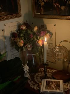 a candle is lit on a table with flowers and music sheets in front of it