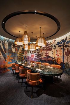 a dining room with an artistic wallpaper and chandelier above the long table