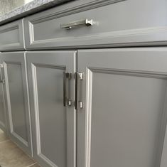 a kitchen with gray cabinets and marble counter tops