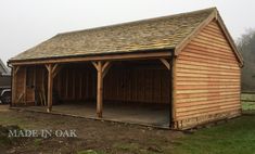 a large wooden garage sitting on top of a lush green field next to a truck