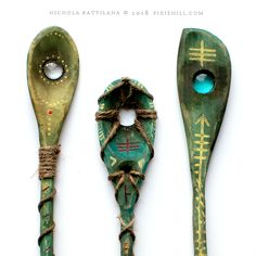 three wooden spoons with designs on them are next to each other and tied together