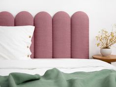 a bed with a pink headboard and pillows on top of it next to a table