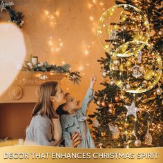 two young children are playing near a christmas tree with the words, decor that enhances christmas spirit