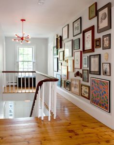 a staircase with many framed pictures on the wall and wood flooring in front of it