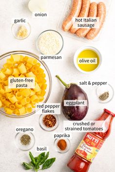 ingredients to make pasta laid out on a white counter top, including eggplant, red pepper, parmesan cheese, and basil