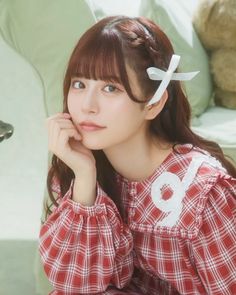 a young woman sitting on top of a couch next to a teddy bear wearing a red and white checkered shirt