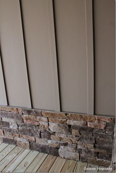 a dog is standing on the porch next to a stone wall and wood flooring